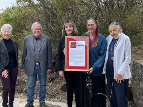 Four women and one man get photographed with a resolution being shared by the center women.